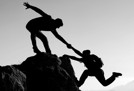 Photo noir et blanc d'un alpiniste aidant un autre alpiniste à gravir un sommet